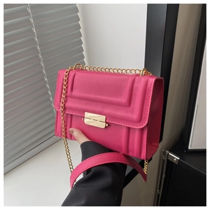 Detail of fuchsia square bag with geometric embossing and gold chain strap