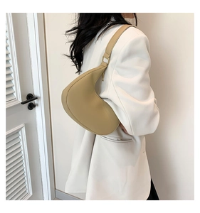 Détail d'un sac hobo croissant kaki en cuir mat porté à l'épaule pour un style moderne