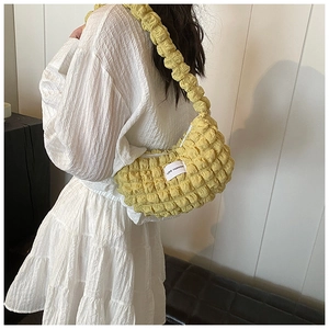 Detail of yellow popcorn fabric crescent bag with ruffled shoulder strap and woven label