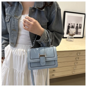 Detail of light blue crossbody bag featuring silver buckle and contrast stitching
