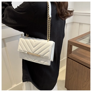 Detail of white quilted crossbody bag with golden metal trim and elegant chain strap