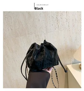Detail of vintage black drawstring bucket bag with gold chain strap on display