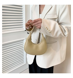 Détail d'un sac à main beige en forme de croissant en similicuir lisse avec fermeture éclair