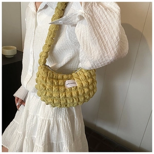 Fashionable mustard yellow bubble textured crescent bag worn with a white dress