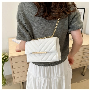 Back view of model wearing white quilted crossbody bag with gold chain and chevron texture