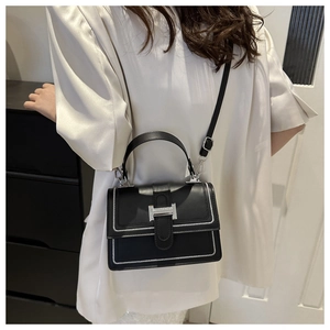 Detailed close-up of black crossbody bag with white stitching and silver H-clasp