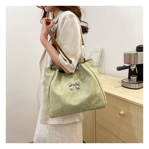 Close-up of mint green velvet tote bag with silver butterfly buckle and brown shoulder strap