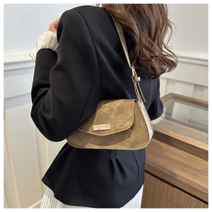 Brown suede underarm bag detail styled with a black blazer and white pleated skirt