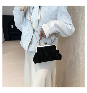 Detail of black velvet evening bag with vintage gold metal handle and chain strap