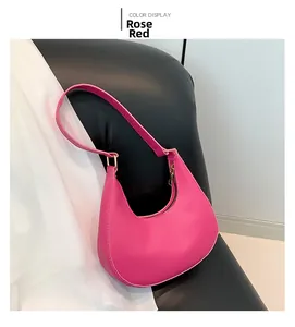 Détail du sac croissant fuchsia avec fermeture dorée posé sur un siège en cuir