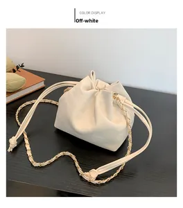Detail of cream white faux leather bucket bag with chain strap on a wooden desk