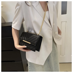 Close-up of black chevron quilted texture and elegant gold chain strap on shoulder bag