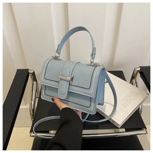 Detail of light blue faux leather handbag featuring white contrast stitching and silver lock