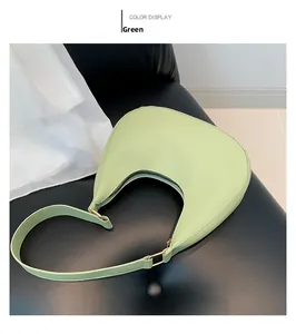 Détail d'un sac hobo vert clair avec boucles dorées posé sur un siège en cuir noir