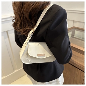 Rear view of a white leather shoulder bag featuring a stylish metal clasp on a model
