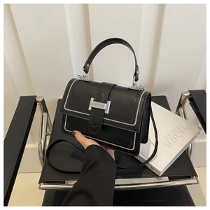 Detail of black leather handbag with white contrast stitching and silver metal buckle