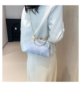 Close-up of light blue pleated fabric handbag with gold metal clasp and chain strap