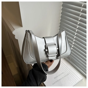 Detail shot of silver metallic shoulder bag featuring large chrome buckle and leather strap