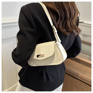 Close-up of cream white baguette bag with structured pleats and gold buckle on shoulder