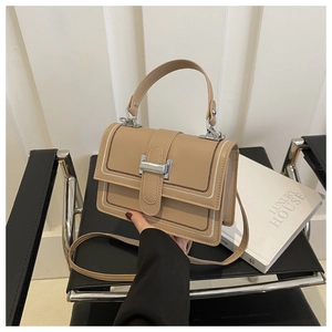 Detail of khaki crossbody bag featuring white stitching and silver rectangular buckle