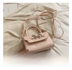 Detail of pink crossbody bag with silver metallic bow buckle and top handle