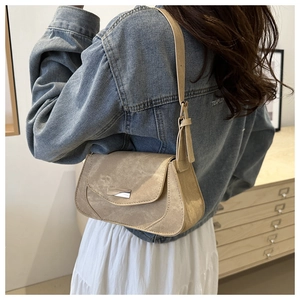 Close-up of beige suede shoulder bag with silver metal buckle on a fashion model