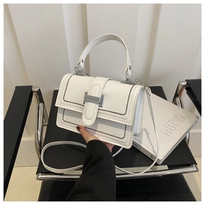 Detail of white PU crossbody bag with black contrast stitching on a stylish chair