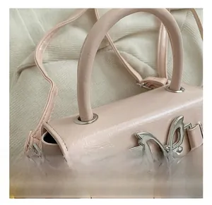Close-up of pink mini handbag showing silver butterfly metal buckle and leather texture