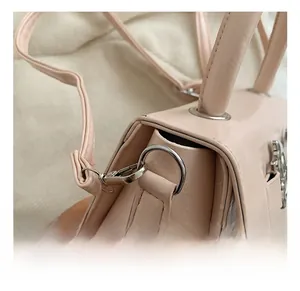 Detail of pink patent leather bag showing silver metal hook and reinforced handle strap