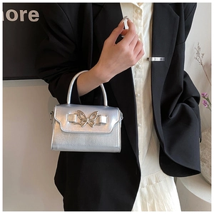 Close-up of metallic silver handbag with bow buckle and textured pleated leather surface