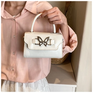 Close-up of white crossbody bag featuring a large silver butterfly metal buckle