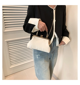 Detail of white satin frame bag with golden clasp, pearl handle and chain strap