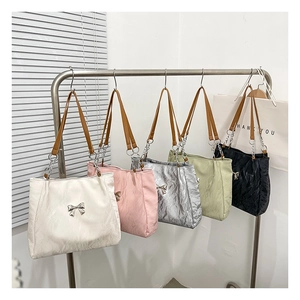 Close-up of colorful pleated tote bags featuring metallic butterfly charms and chain straps