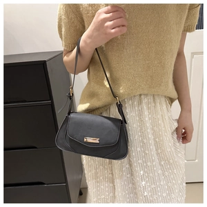 Detail of minimalist black underarm bag with gold rectangle buckle and adjustable strap