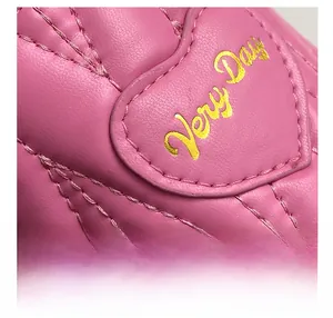 Detail of pink quilted leather bag with heart patch and golden Very Day lettering