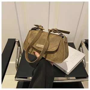 Detail of a brown textured crossbody bag with a gold metal buckle and adjustable strap