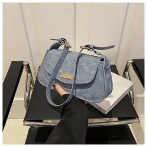 Detail of blue denim shoulder bag with golden metallic hardware and adjustable strap