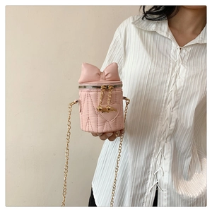 Detail view of pink quilted bucket bag with 3D bow accent and gold chain strap