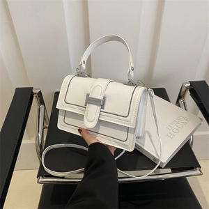 White faux leather crossbody bag with contrasting black stitching and silver metal clasp