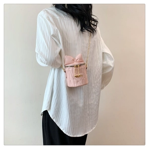 Pink quilted mini bucket bag with bow detail and gold chain strap on female model