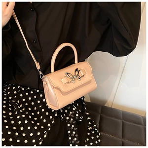 Pink crossbody bag with a metal butterfly buckle shown as a handheld fashion accessory