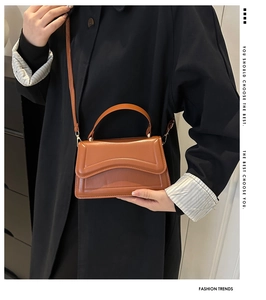 Detailed side view of caramel brown leather handbag with wavy flap and adjustable strap