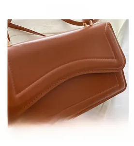 Close-up of caramel leather handbag featuring wavy flap edge and gold hardware detail