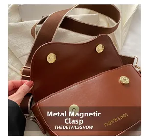 Détail du sac selle marron avec double fermoir magnétique doré et logo embossé chic