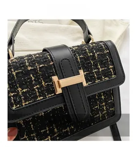 Nahaufnahme der schwarzen Hahnentritt-Tasche mit goldenem H-Verschluss und Ledergriff