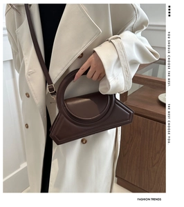 Detail view of a vintage dark brown leather crossbody bag with a circular top handle