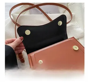 Detailed close-up of the secure gold magnetic snap closure on a brown leather handbag