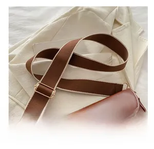 Détail du sac besace marron avec large bandoulière en tissu et boucle dorée