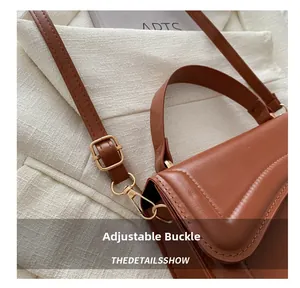 Detail of adjustable gold buckle and leather handle on a brown vintage handbag
