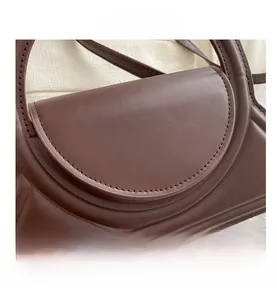 Detail of brown leather handbag featuring arched flap and meticulous stitching